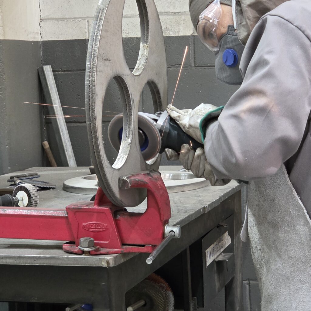 Técnico realizando o acabamento e a fabricação de componentes de um filtro industrial sob demanda em oficina especializada.